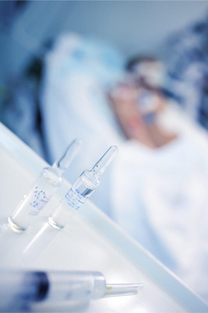Ampullen, Spritzen - Im Hintergrund Krankenbett mit Patient