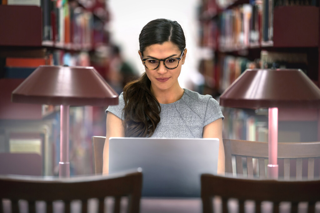 Junge Frau am Laptop in Bibliothek
