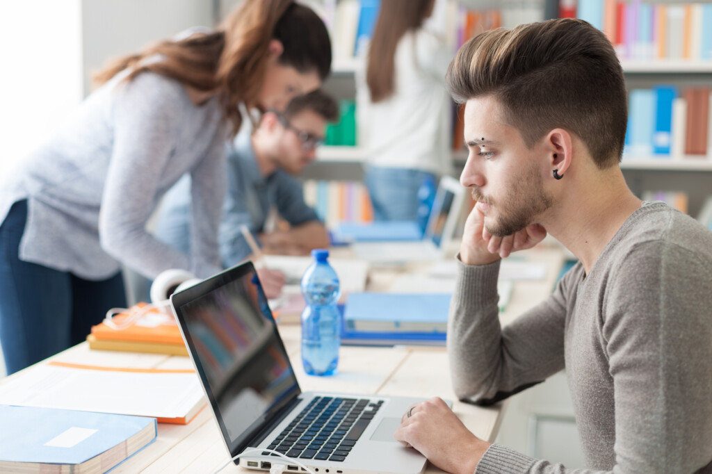 Student in Bibliothek mit Laptop _ Karrierewege für Geisteswissenschaftler
